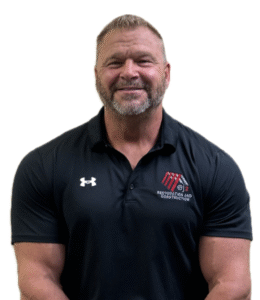 Smiling muscular man in a black polo shirt with a Restoration and Construction logo on the chest (company branding).